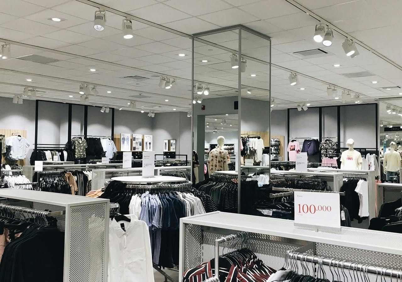 A clothing store interior featuring various clothes displayed on racks and hanging from the ceiling.